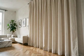 Salon moderne parisien avec de grands rideaux en lin ivoire tombant jusqu'au parquet en chêne clair, ambiance chaleureuse et épurée