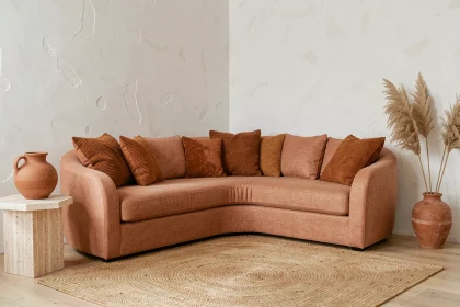 Salon contemporain décoré dans des tons terracotta avec canapé en lin courbé, vase en céramique et tapis en jute sur parquet chêne clair