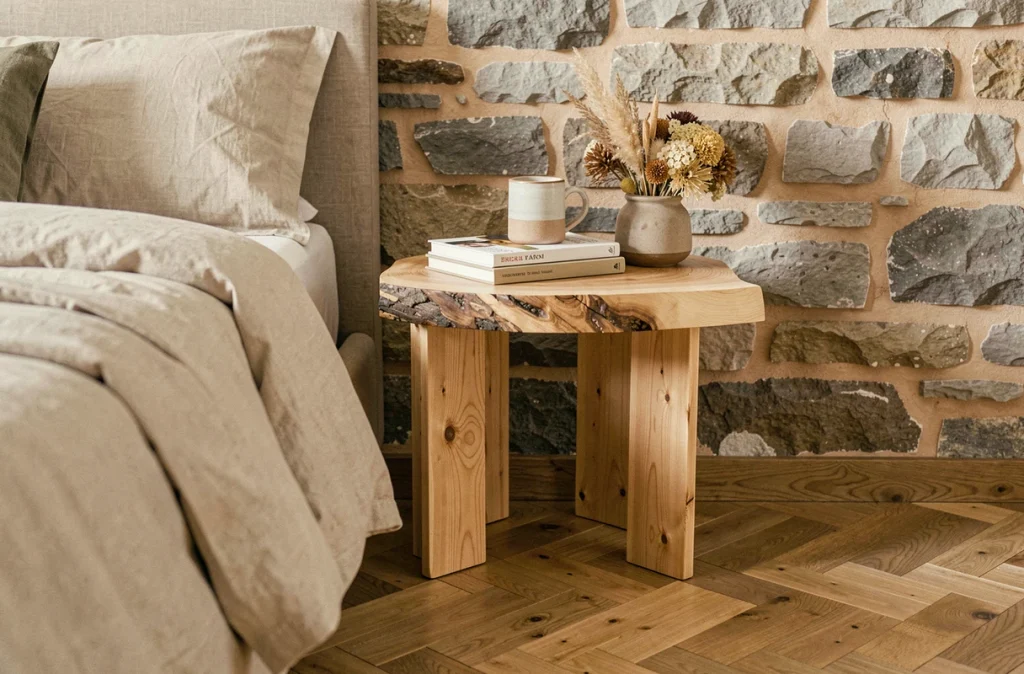 Table de chevet en pin brut avec plateau bord vivant dans une chambre contemporaine aux murs en pierre apparente